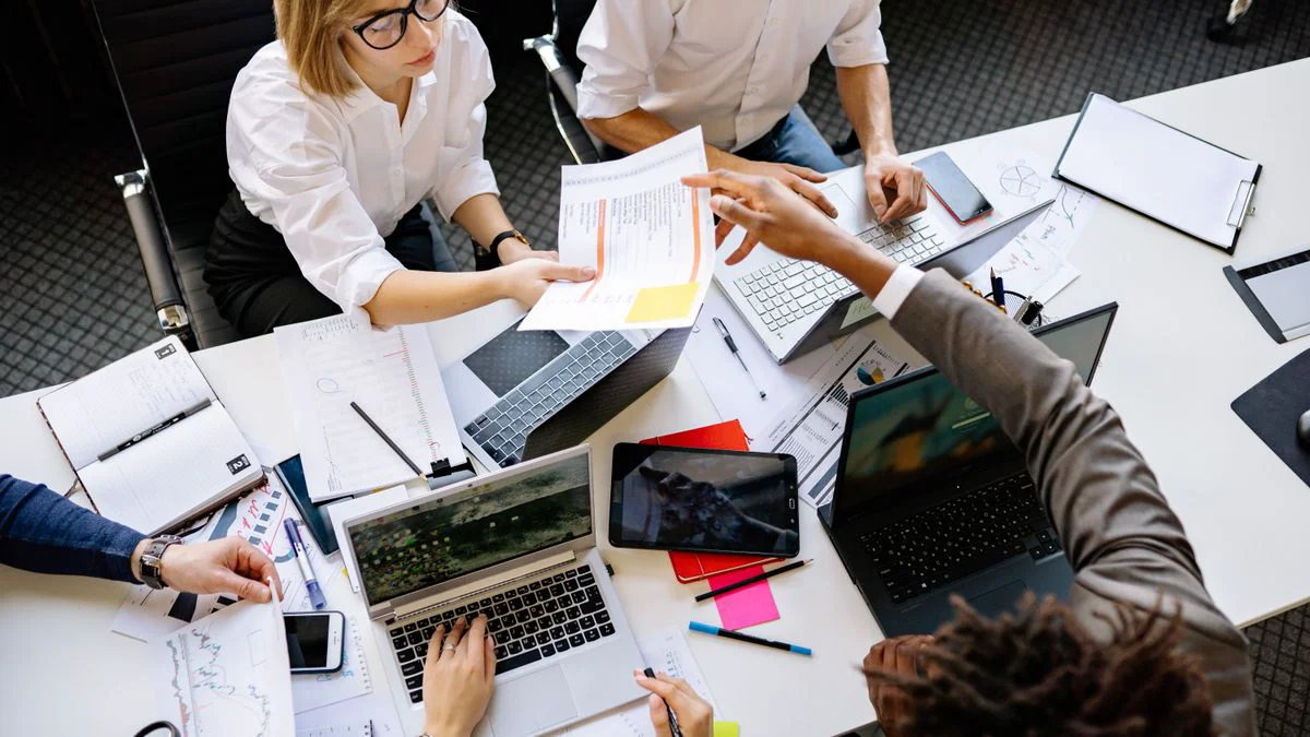A startup team reviews costs and growth plans around a laptop and printed notes