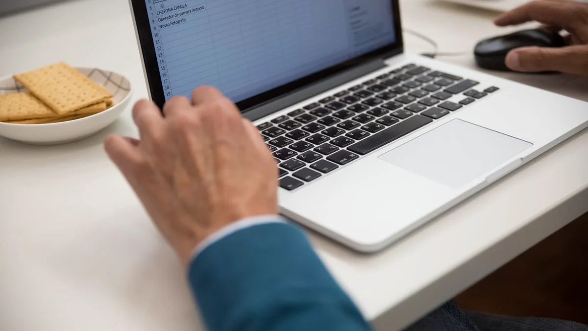 Person reviewing spreadsheet records on a laptop in an office