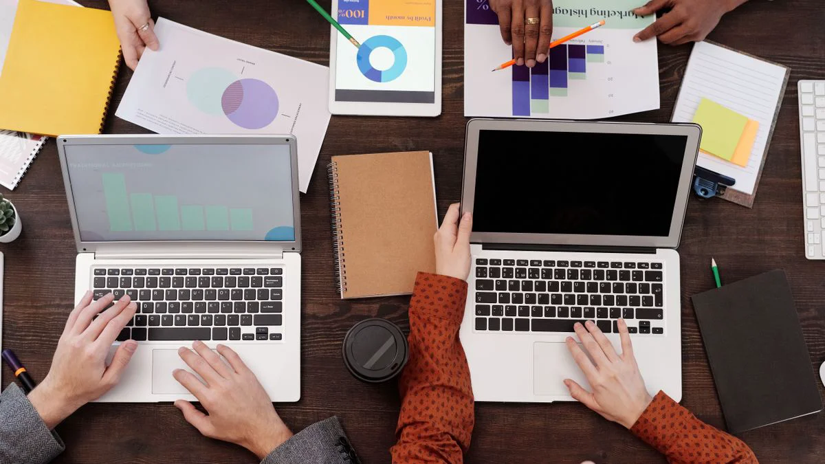 A marketing team reviewing buyer questions on a laptop and printed notes