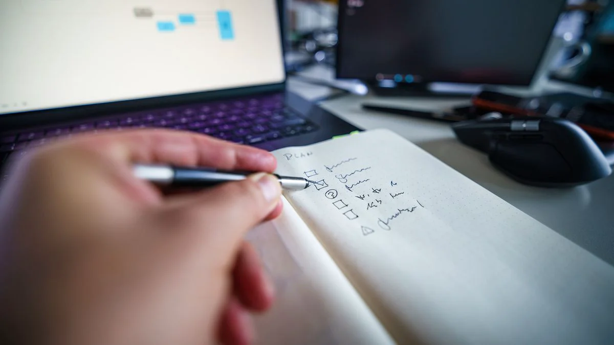 A checklist on a desk next to a laptop showing a structured content review process
